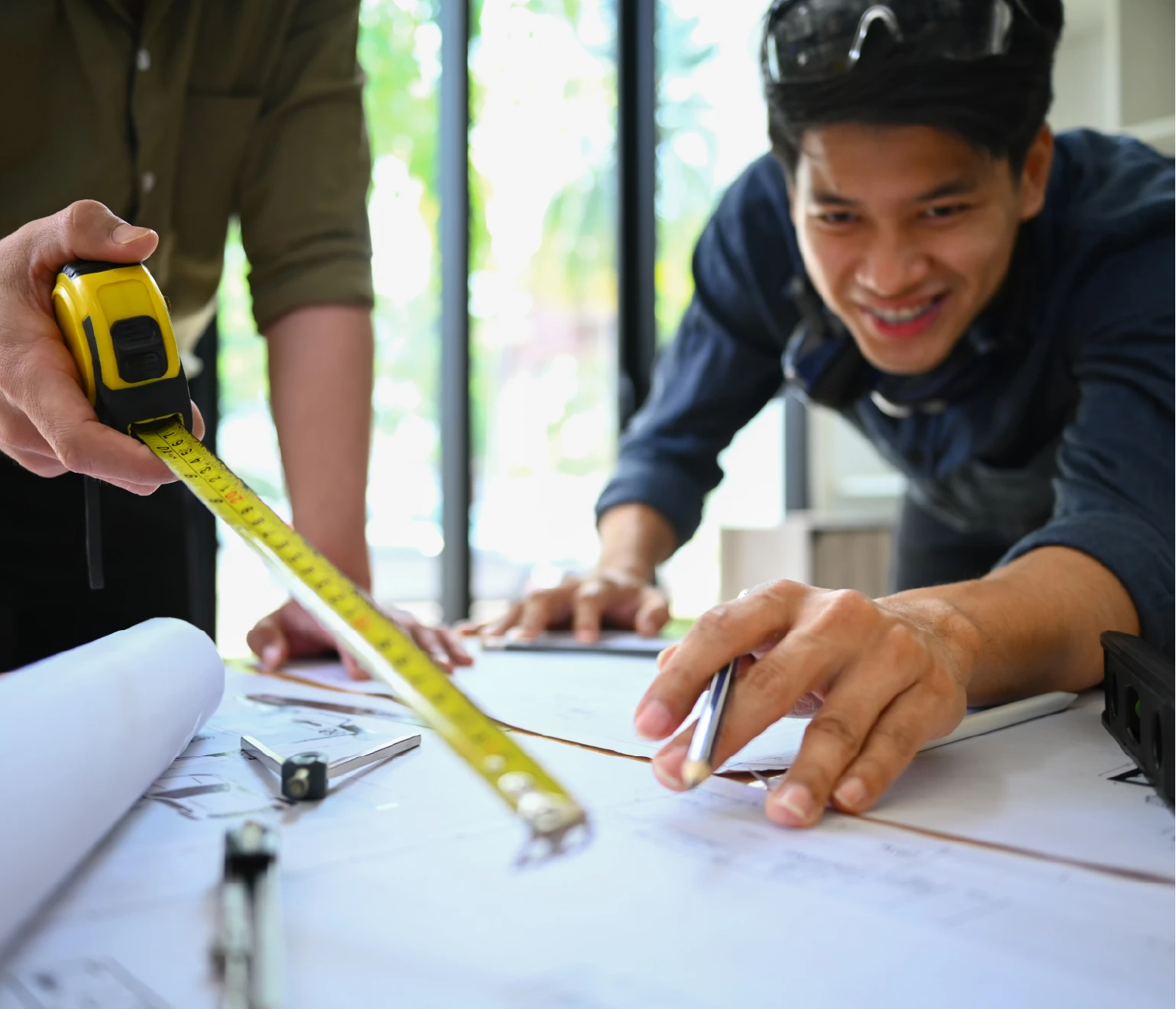 Deux experts analysant un plan de construction de piscine, prise de mesure et validation des choix techniques.