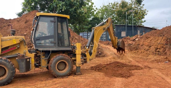 Engin de chantier effectuant le terrassement sur un terrain en terre rouge, préparation du sol avant construction d’une piscine