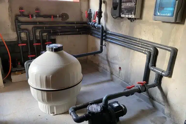 Local technique de piscine équipé d’une pompe et d’un filtre à sable reliés au circuit hydraulique