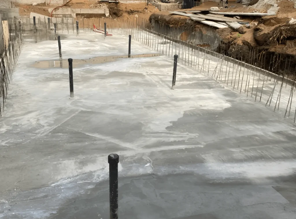 Radier de piscine en béton armé avec fers d’attente pour les murs et canalisations verticales.