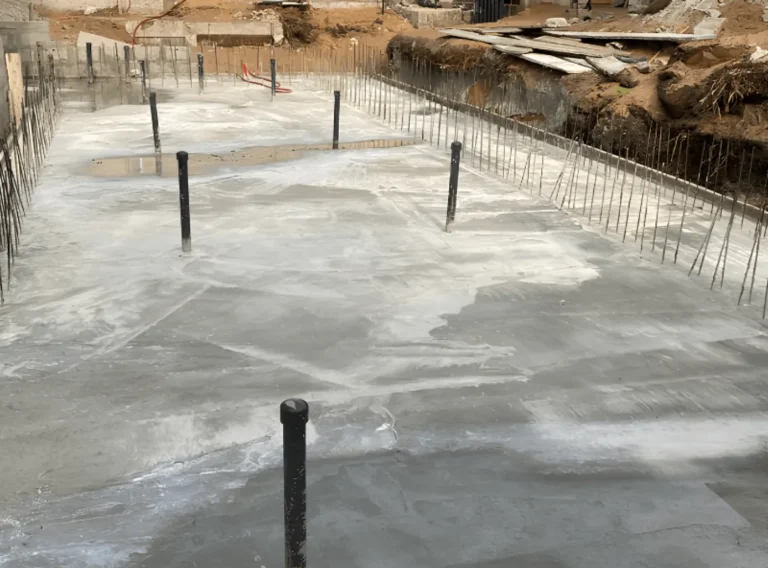 Radier de piscine en béton armé avec fers en attente pour les murs et tuyaux bonde de fond et refoulements de fond.