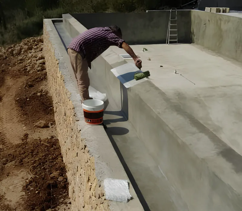 Finition d'une goulotte de débordement miroir en béton en cours de construction