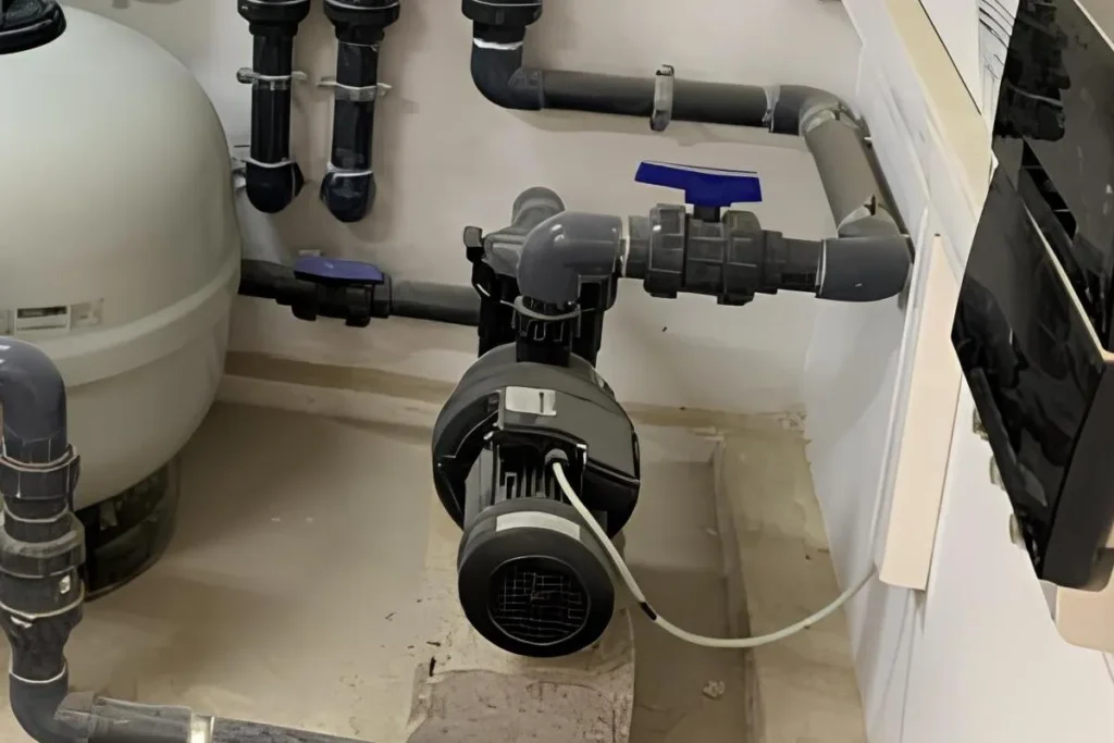 Pompe de piscine installée dans un local technique avec filtre et réseau hydraulique
