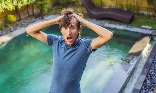 Autoconstructeur frustré devant sa piscine à l'eau verte suite aux erreurs d'autoconstruction