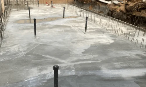 Radier de piscine en béton armé avec fers d’attente pour les murs et canalisations verticales.